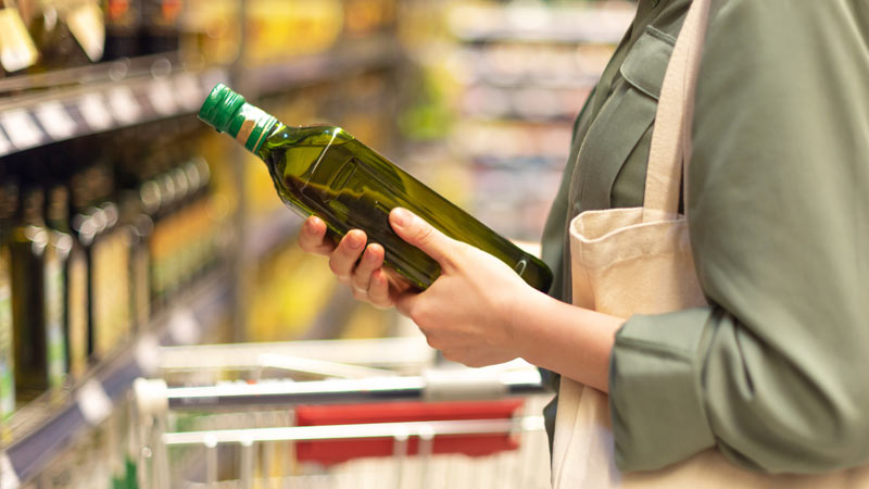 Mulher a comprar azeite no supermercado